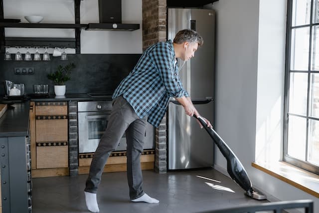 A man cleaning the floor with a cleaning vacuum