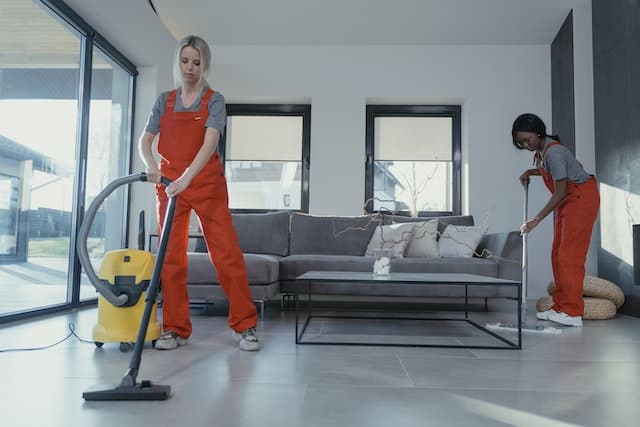 Two women in orange remove stubborn grease stains from floors