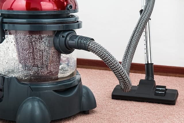 A black and red vacuum cleaner on a carpeted floor