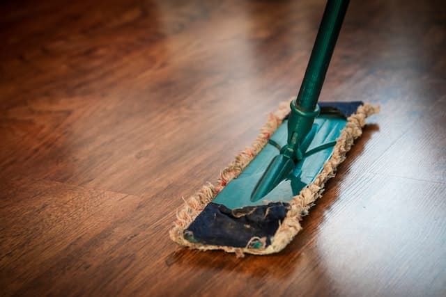 A green mop on a wooden floor